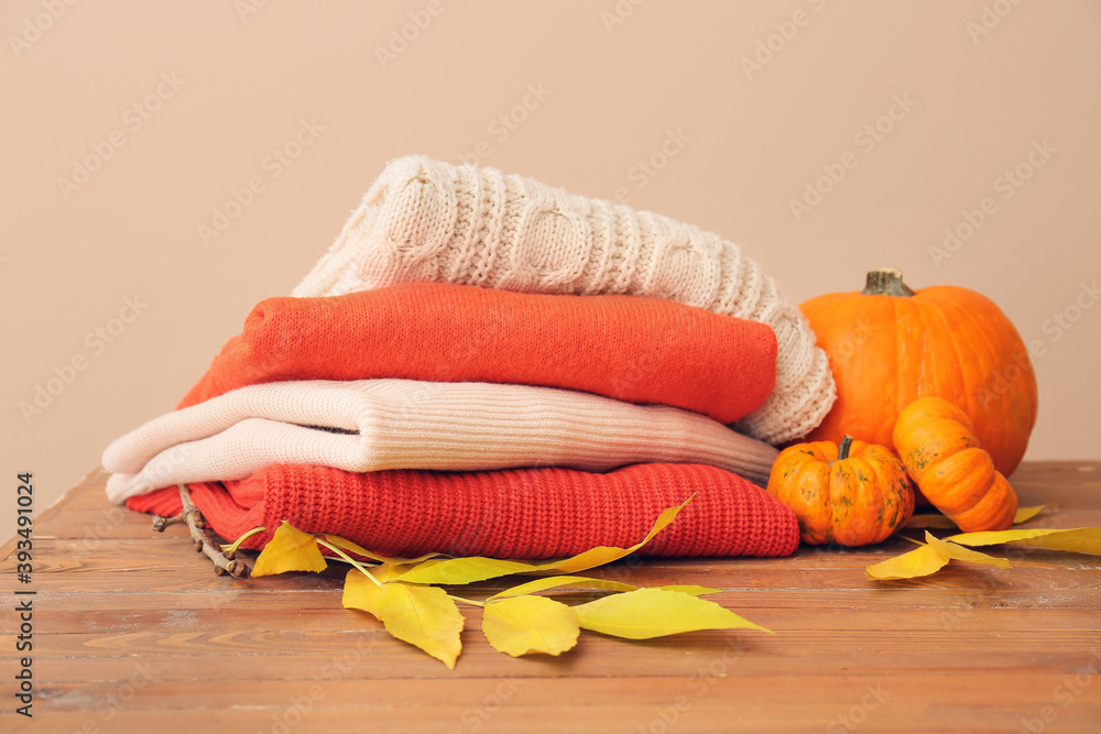 Autumn composition with stylish clothes on table against color background