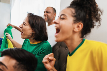 Wall Mural - real latin american family watching football on television, celebrating goal of brazil