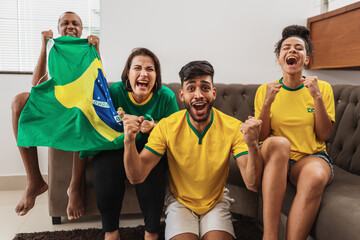 Wall Mural - real latin american family watching football on television, celebrating goal of brazil