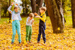 © Iryna - Three children in park playing with fallen leaves. Delighted happy school kids friends having fun throwing fallen leaves up in autumn park.