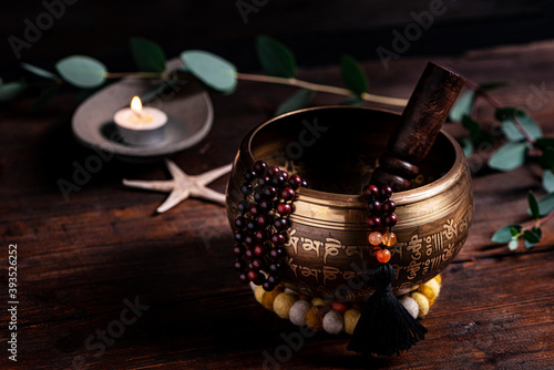 Close-up of a singing bowl and prayer beads (mala) for chanting mantras as a decoration on an old wooden board