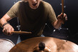 © LIGHTFIELD STUDIOS - Cropped view of musician with open mouth holding drumsticks and playing cymbal on blurred background