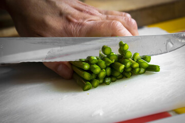 Canvas Print - Selective focus shot of a man cutting asparagus on a cutting board