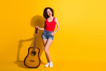 Poster - Full length body size view of nice attractive pretty dreamy cheerful wavy-haired girl pop star holding guitar creating new live sound show isolated bright vivid shine vibrant yellow color background