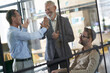 © Kostiantyn - Two excited mature businessmen giving high five to each other while having a meeting with colleagues in the modern office