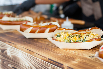 Hot dogs on a wooden table during street food festival. Food display on a outdoor stall.