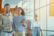 © Kostiantyn - Two young cheerful diverse business people with laptop and smartphone discussing something and smiling while standing in the modern office or coworking space