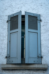 blue wooden shutter at one window half closed