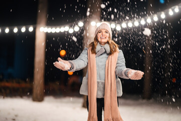 Wall Mural - Beautiful young woman Playing with snow evening in the winter park. Happy  woman having fun on winter holidays. Christmas, New year. Winter lifestyle.