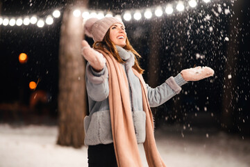 Wall Mural - Beautiful young woman Playing with snow evening in the winter park. Happy  woman having fun on winter holidays. Christmas, New year. Winter lifestyle.