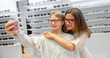 Mother and daughter taking selfies while trying out new glasses at ophthalmologist