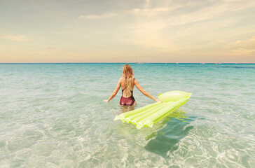 Wall Mural - young woman in a one-piece swimsuit in the sea with an inflatable mattress