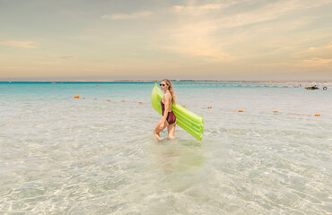 Wall Mural - young woman in a one-piece swimsuit in the sea with an inflatable mattress