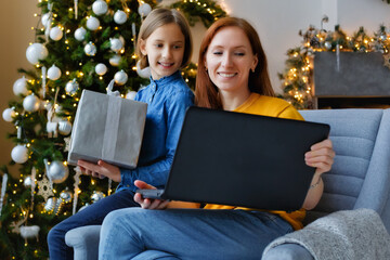 Christmas online family congratulations. Smiling european blonde mother and daughter using mobile tablet for video call friends and parents.