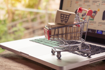 Shopping online concept - Parcel or Paper cartons with a shopping cart logo in a trolley on a laptop keyboard. Shopping service on The online web. offers home delivery..