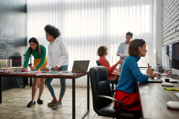 Design studio. Group of young creative people working and discussing fresh ideas in the modern office. Web designers in casual wear working together