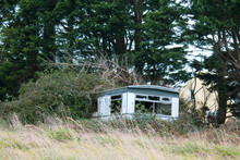 Abandoned And Broken Mobile Home Trailer Falling Apart In The Tall Grass And Forest.