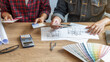 © PIC SNIPE - Interior designer and Architect choosing color in color swatch samples chart for house coloring selection in office with blueprint. Construction concept.
