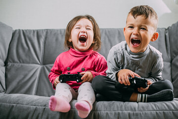 Brother and sister with a gamepad in their hands playing games shouting having fun