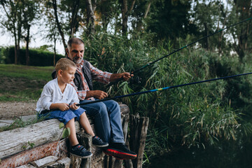 Wall Mural - boy fishing on the lake with his grandfather