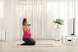 © Ljupco Smokovski - Pregnant woman kneeling and exercising with dumbbells in front of tv