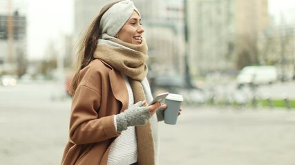 Wall Mural - smiling woman using mobile phone while having a coffee in downtown area