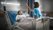 © Gorodenkoff - Hospital Ward: Friendly Hispanic Head Nurse Gives High Five to a Happy Female Patient Recovering in Bed. Professional Nurse Helps Happy Woman Get Better after Surgery.