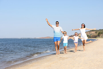 Poster - Happy family walking on sandy beach near sea. Summer holidays