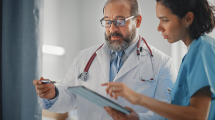 Modern Hospital Ward: Experienced Latin Doctor Talks With Professional Head Nurse. They Use Touchscreen Computer to Discuss Treatment Plan. Health Care Specialists Discussing Test Results.