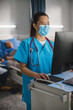 © Gorodenkoff - Hospital Ward: Vertical Portrait Shot of a Professional Experienced Chinese Head Nurse / Doctor Wearing Face Mask Uses Medical Touch Screen Computer, Checking Patient's Medical Data, Treatment Plan.