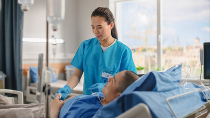 Hospital Ward: Friendly Chinese Head Nurse Connects Finger Heart Rate Monitor / Pulse oximeter to Male Patient Resting in Bed. Nurse Checks Man Getting well after Surgery.