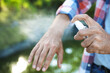 Man applying insect repellent onto hand outdoors, closeup