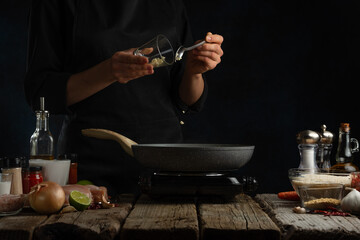 Wall Mural - Professional chef pours rice into pan with chicken fillet. Backstage of cooking traditional Indian chicken curry on dark blue background. Frozen motion. Concept cooking process. Frozen motion.