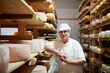 © .shock - Cheese maker at the storage with shelves full of cow and goat cheese