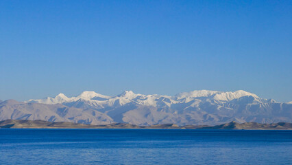 View from the shores of Karakul lake after sunrise, with Trans-Alai snow-capped mountain range in the background, Murghab district, Gorno-Badakhshan, in the Pamir region of Tajikistan