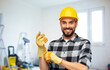 © Syda Productions - repair, construction and work concept - happy smiling male worker or builder in helmet and gloves over room with building equipment background