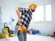 © Syda Productions - health, construction and repair concept - male worker or builder in helmet having back ache over room with building equipment background