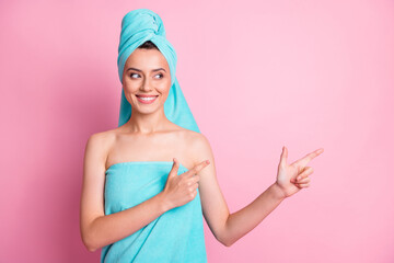 Sticker - Photo of optimistic cute young lady pointing empty space wear teal bath towels on head body isolated on pink color background