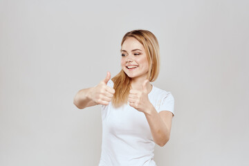 Poster - cheerful blonde in a white t-shirt gesturing with her hands light background