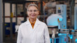 © nimito - Mature woman scientist in protective glasses and lab coat standing at chemical manufacturing