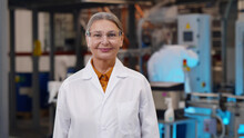 Mature Woman Scientist In Protective Glasses And Lab Coat Standing At Chemical Manufacturing