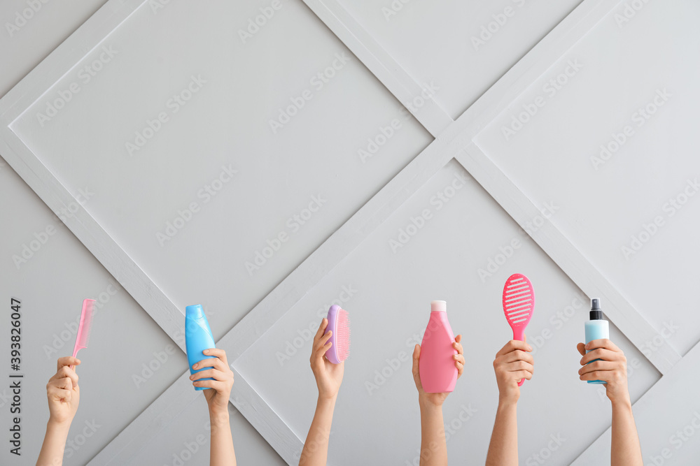 Female hands with hair tools on light background