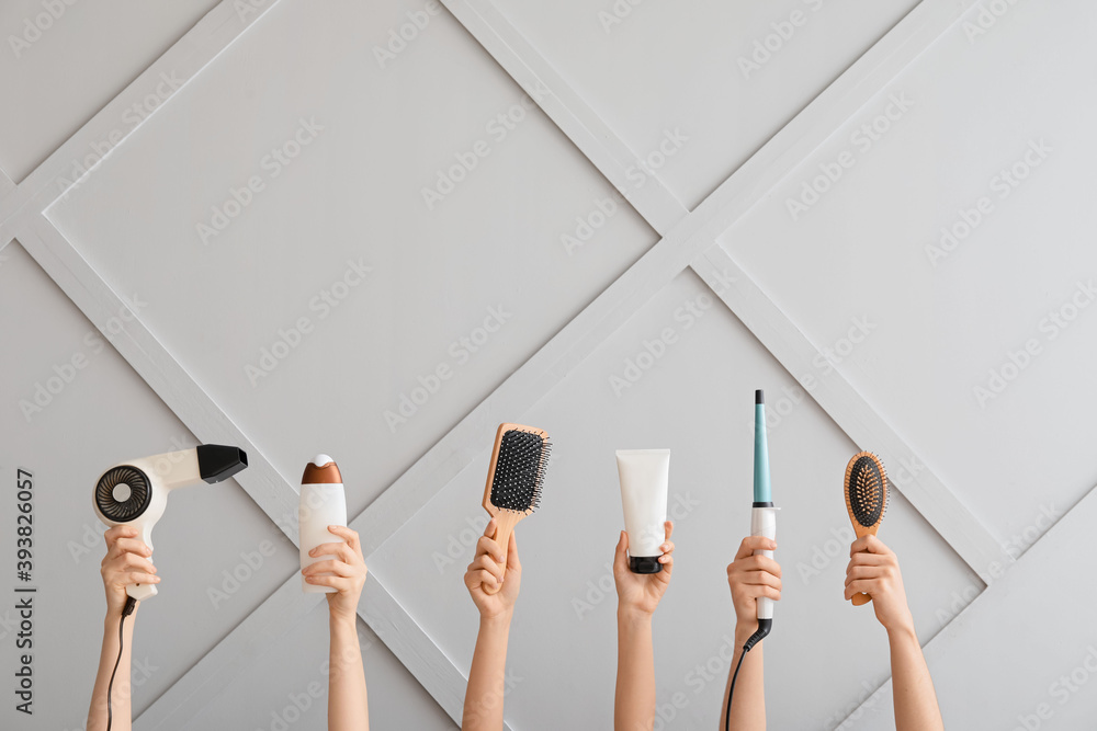 Female hands with hair tools on light background