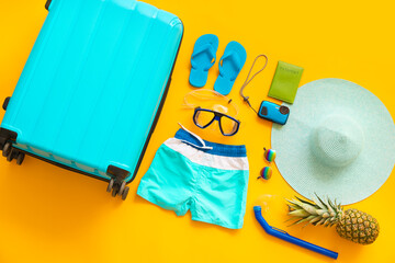 Set of beach accessories with suitcase on color background. Concept of rest abroad