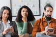 © LIGHTFIELD STUDIOS - woman messaging on mobile phone while focused hispanic colleagues listening business lecture