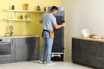 Poster - Worker repairing fridge in kitchen