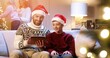 © VAKSMANV - Portrait of joyful Caucasian dad with teen boy sitting in cozy room typing on tablet buying xmas gifts on internet. Mom and small girl decorating glowing Christmas tree. Family holidays concept