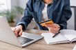 © LIGHTFIELD STUDIOS - partial view of young woman holding credit card near laptop on desk
