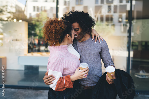 Young romantic diverse couple with takeaway coffee embracing on street