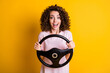 © deagreez - Photo portrait of amazed girl learning to drive keeping steering wheel staring smiling isolated on vivid yellow color background